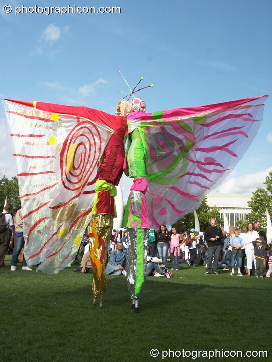 Women wearing bright winged costumes gracefully dance on stilts at the Thames Festival 2004. London, United Kingdom. © 2004 Photographicon