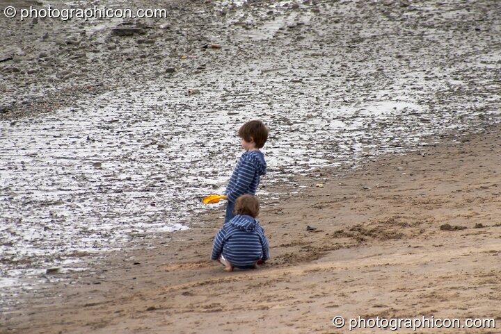 Two small boys play at a Reclaim The Beach party on the sandy river bank at the Thames Festival 2004. London, United Kingdom. © 2004 Photographicon