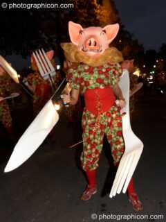 Person dressed as a pig carrying a very large plastic knif and fork during the carnival at the Thames Festival 2005. London, United Kingdom. © 2005 Photographicon