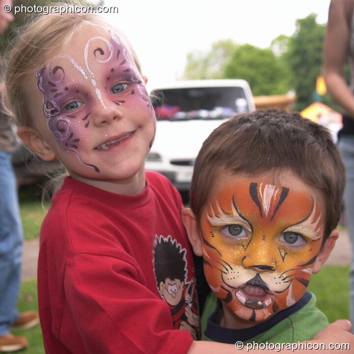 Small boy with face professionally pained as a tiger being hugged by his sister at Kingston Green Fair 2004. Kingston Upon Thames, United Kingdom. © 2004 Photographicon