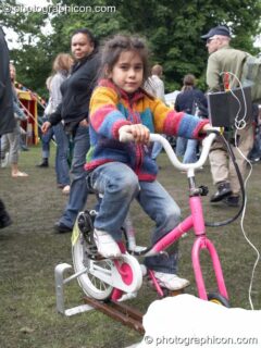 A girl inflates a pedal-powered model provided by The Campaign for Real Events at Kingston Green Fair 2006. Kingston upon Thames, United Kingdom. © 2006 Photographicon