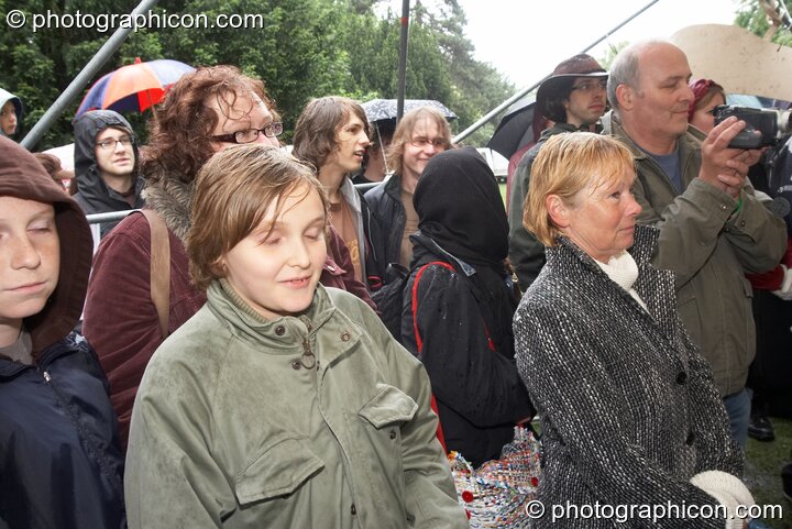 A crowd huddle in the rain to watch Green Rock River Band at Kingston Green Fair 2007. Kingston upon Thames, United Kingdom. © 2007 Photographicon