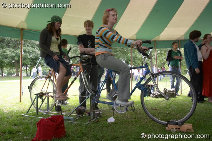 People pedaling to generate power for a stage at the London Green Lifestyle Show 2005. London, United Kingdom. © 2005 Photographicon