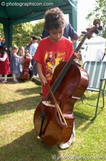A boy plays with a cello provided by Surrey Strings at the London Green Lifestyle Show 2005. London, United Kingdom. © 2005 Photographicon