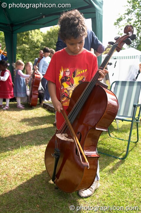 A boy plays with a cello provided by Surrey Strings at the London Green Lifestyle Show 2005. London, United Kingdom. © 2005 Photographicon