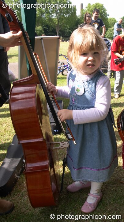 A little girl plays with a cello provided by Surrey Strings at the London Green Lifestyle Show 2005. London, United Kingdom. © 2005 Photographicon