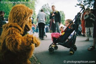Man in gorilla costume talks to girl in push chair at Kingston Green Fair 2003. Kingston upon Thames, United Kingdom. © 2003 Photographicon
