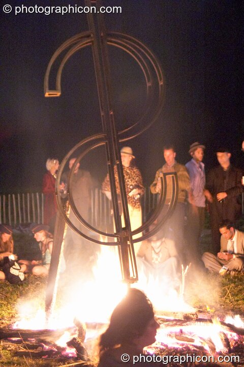 A large metal dollar symbol is roasted in an open fire at the Lost Vagueness Summer Party 2004. Lewes, United Kingdom. © 2004 Photographicon