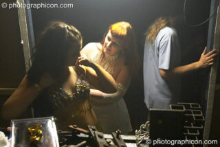 Two women adjust clothing in a make-shift dressing room at the Synergy Project. London, United Kingdom. © 2004 Photographicon