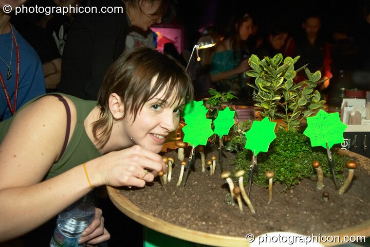 Girl poses with mushrooms for sale at the Synergy Project. London, United Kingdom. © 2004 Photographicon