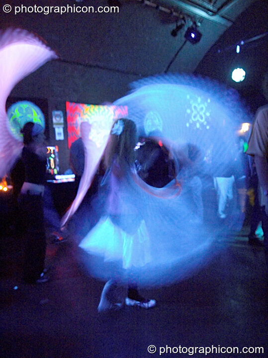 Girl whirling sections of cloth at slow shutter speed under UV light in the Liquid Connective space at the Synergy Project. London, United Kingdom. © 2005 Photographicon