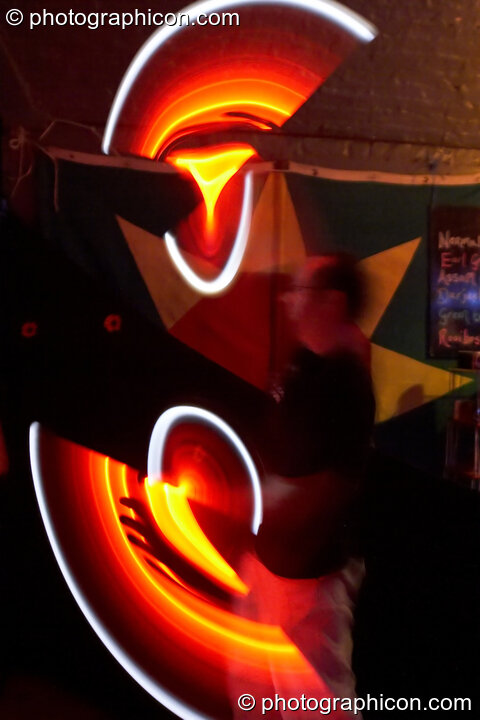 Jedi Juggler with illuminated flashing Glow Staffs, trail-blurred by slow shutter speed, at The Synergy Project. London, United Kingdom. © 2006 Photographicon