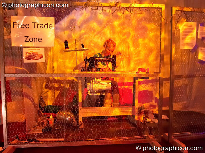 A woman sews behind a fence in the Speak space at The Synergy Project. to raise awareness of the injustice in the garment industry. London, United Kingdom. © 2006 Photographicon