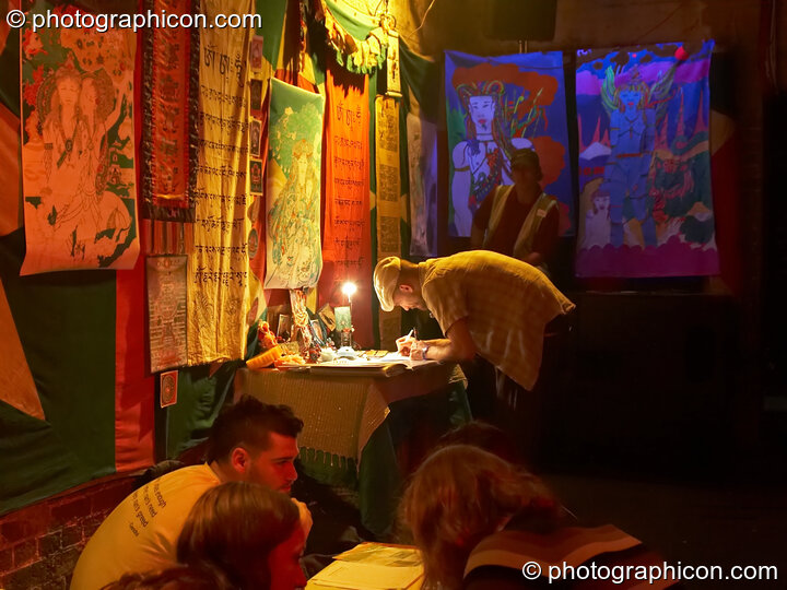 A man writes his thoughts on a stall in the Small World Stage at The Synergy Project. London, United Kingdom. © 2007 Photographicon