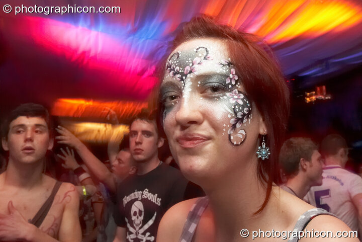 A woman with enigmatic expression and painted face dances to an illuminated backdrop in the Mistzfiedmind space at The Synergy Project. London, United Kingdom. © 2007 Photographicon