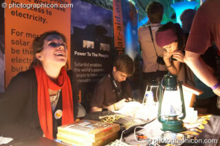 A group of people gathered around the SolarAid stall in the Folktronica room at The Synergy Project. London, United Kingdom. © 2008 Photographicon