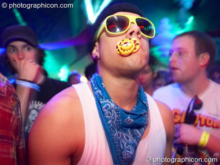 A man wearing yellow glasses sucks a dummy in the Blood Tribe Records room at Luminopolis (formerly The Synergy Project). London, United Kingdom. © 2008 Photographicon