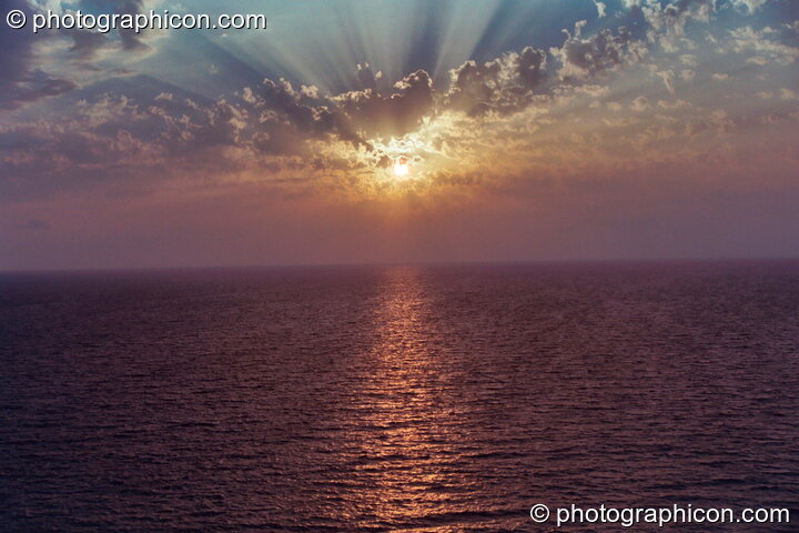 The setting sun through the gaps in the cloud at Agios Pavlos. Agios Pavlos, Greece. © 2002 Photographicon