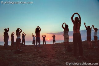 A group of people practising Tai Chi as the sun sets on a cliff at Agios Pavlos. Agios Pavlos, Greece. © 2002 Photographicon