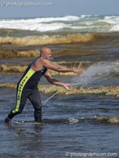 Man casts net into shallow waters of the red-brown sea at False Bay, Cape Town - Western Cape, South Africa. Cape Town, South Africa. © 2005 Photographicon